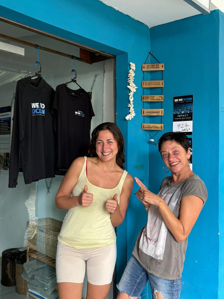 Tauchschülerin nach erfolgreichem OWD-Kurs mit Instruktorin vor dem We Do OCEAN Office, Padang Bai, Bali | Student diver after successfully completing the OWD course with instructor in front of the We Do OCEAN office, Padang Bai, Bali